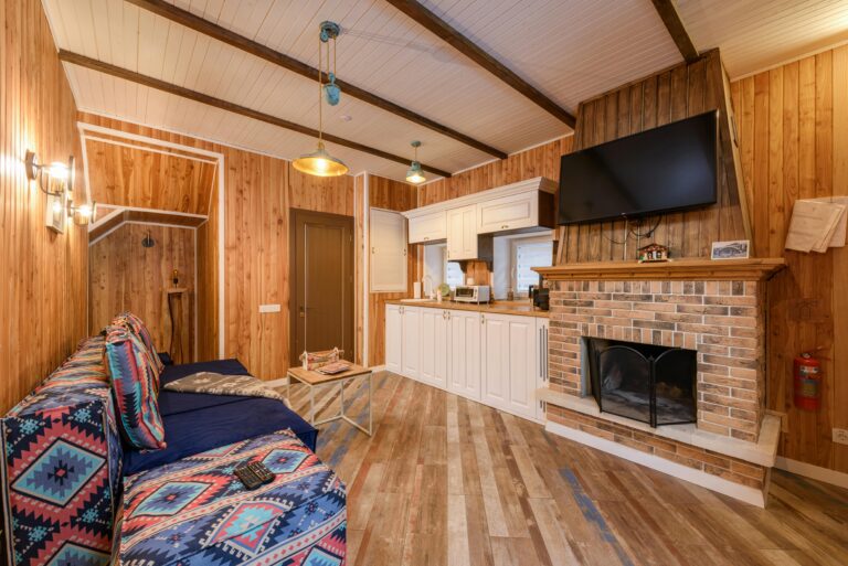 Warm rustic living room featuring wooden walls, a brick fireplace, and cozy seating area with modern amenities.