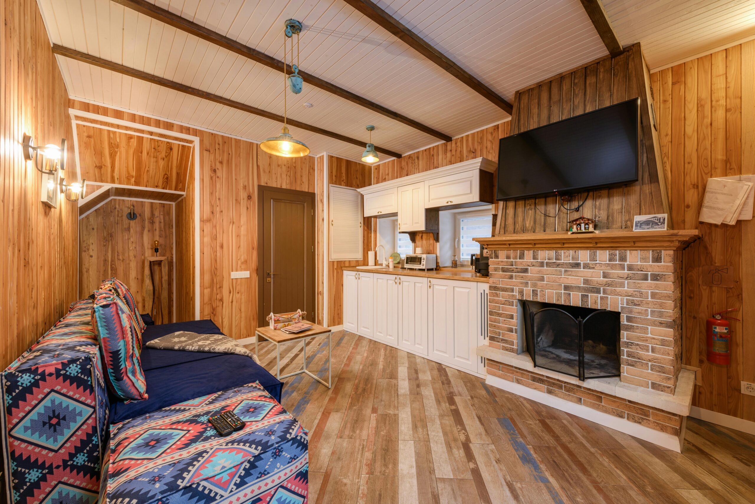 Warm rustic living room featuring wooden walls, a brick fireplace, and cozy seating area with modern amenities.